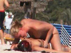Voyeur grabando a dos amigas lesbianas dándose cariño en la playa