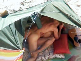 Voyeur con una cámara de video filmando a parejas follando en la playa