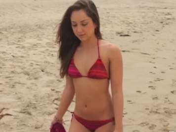 Ragazza del bikini da solo sulla spiaggia guardando pene più grande